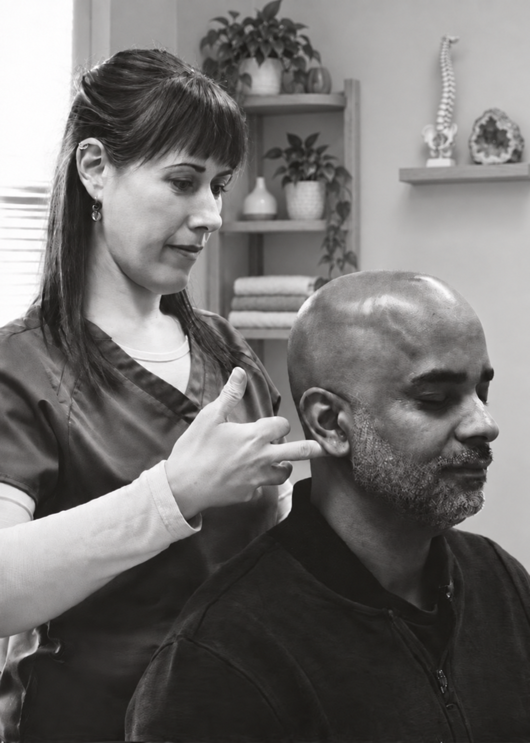 Dr. Hannah Cork standing behind a seated patient, gently adjusting behind the ear